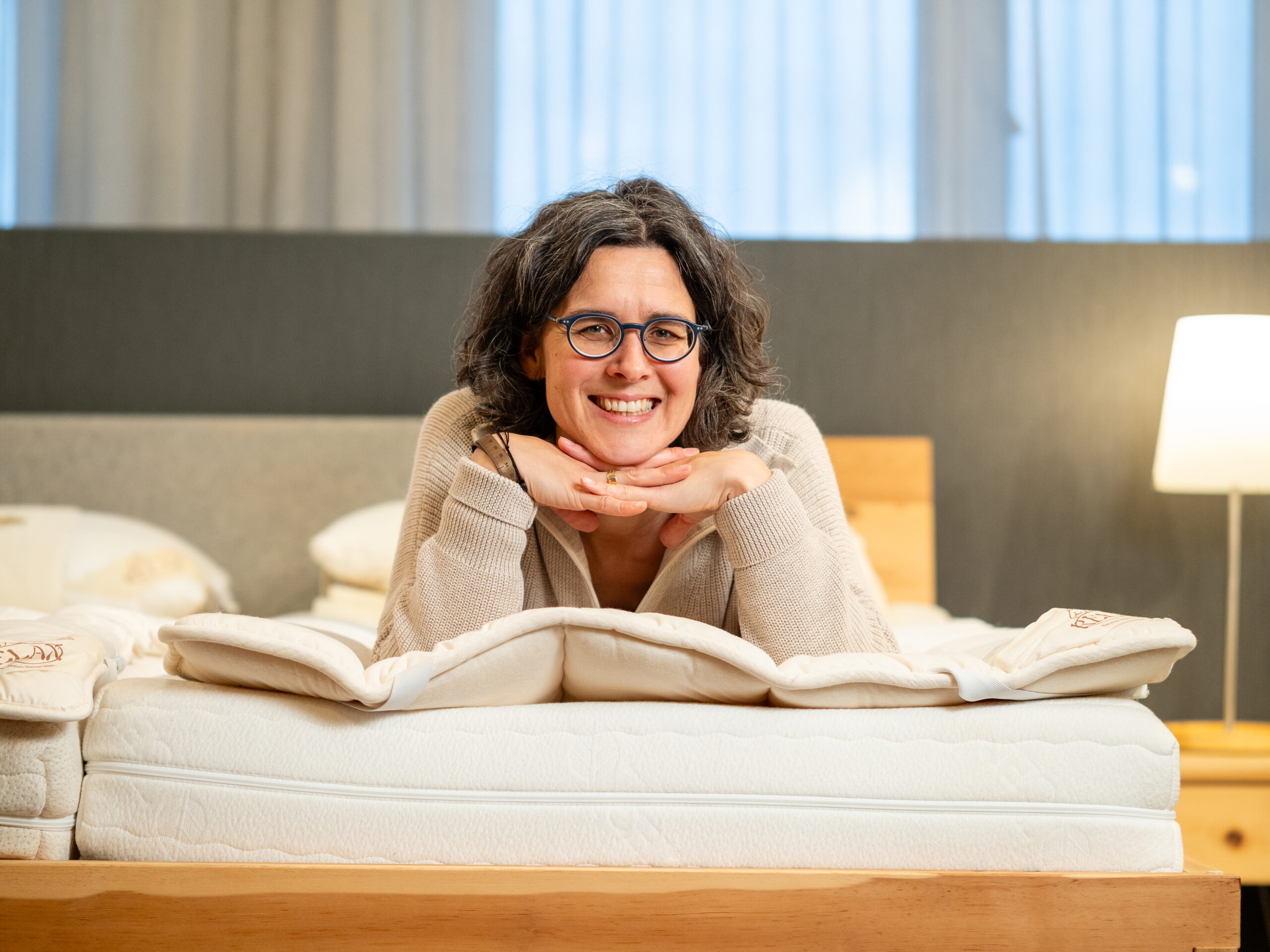 Frau liegt glücklich auf ihrem Bett und genießt die Relaxmatratze.