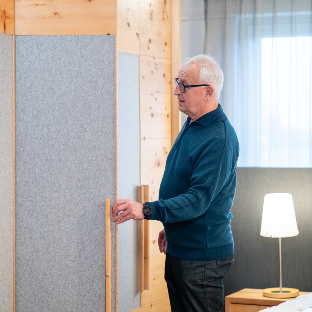 Kunden im Showroom betrachtet den hochwertigen Holzschrank aus Zirbe mit Filzaplikationen.